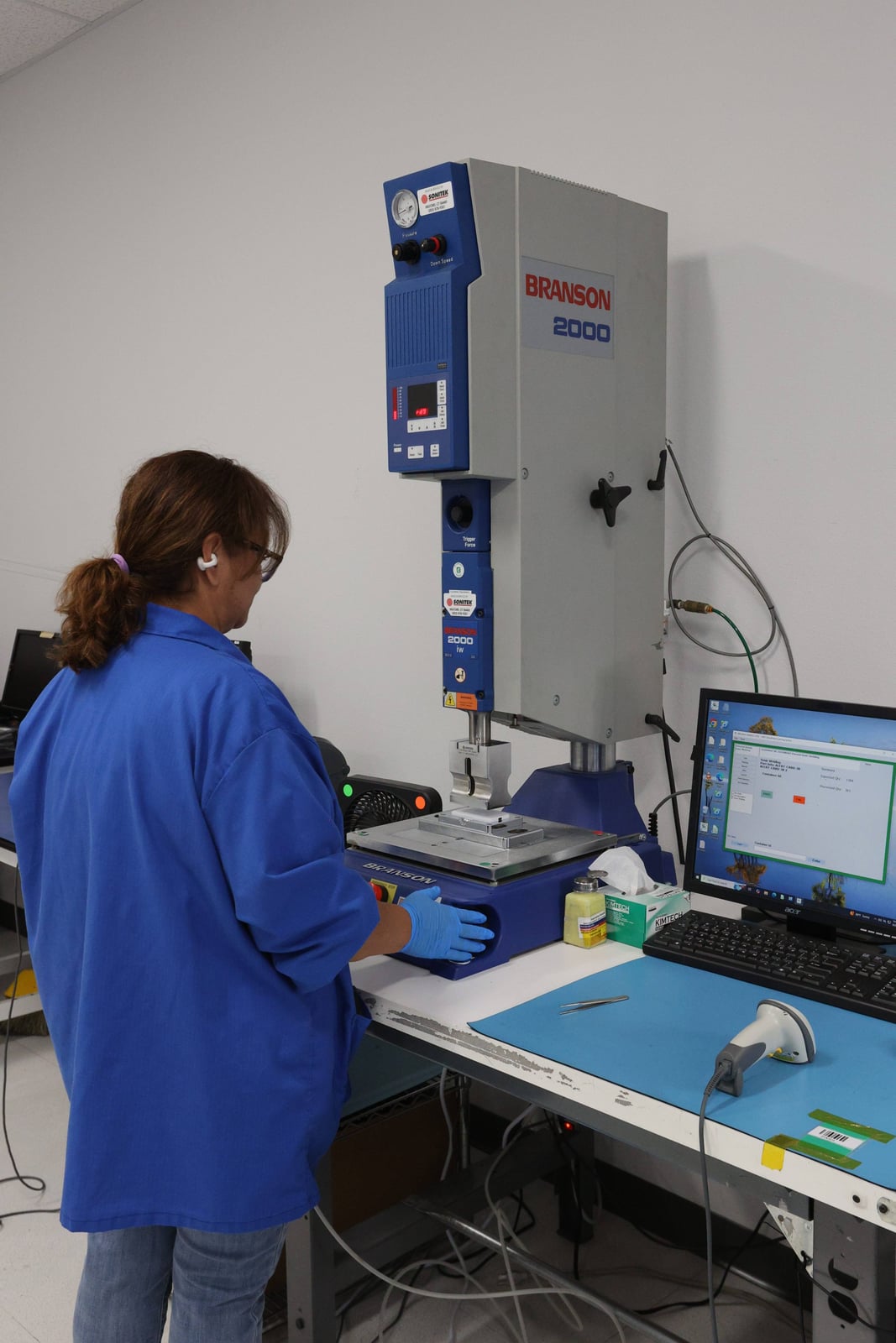 Operator at a Branson ultrasonic assembly workstation in Carlsbad